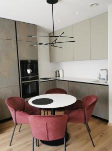 a kitchen with a white table and red chairs at MyCasa CBD in Vilnius