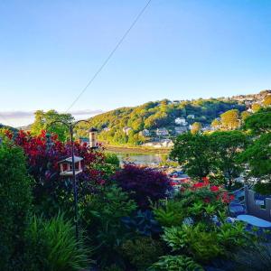 a view of a garden with flowers and a river at Schooner Point Guest House in Looe