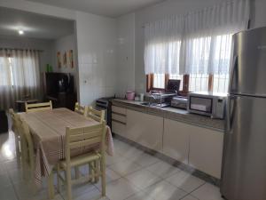 a kitchen with a table and a stainless steel refrigerator at BRUNO KLEMTZ RUA 274 CaSA COM PISCINA PRIVATIVA in Itapema