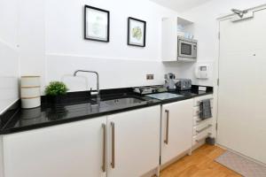 uma cozinha branca com um lavatório e um micro-ondas em Modern studio apartment in Leeds City Centre (LS1) em Leeds