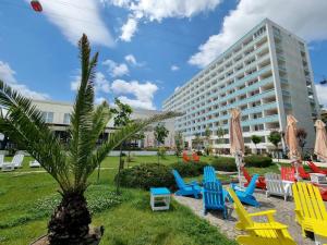a group of chairs and a palm tree in front of a building at Hotel Victoria in Mamaia
