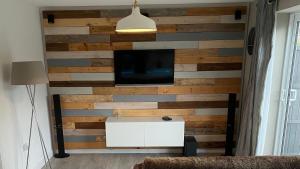 uma sala de estar com uma parede de madeira e uma televisão em Comfortable modern 1bed house 5 mins from centre em Lincoln