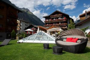 uma mesa de vidro com uma cadeira num campo com um edifício em Tradition Julen Hotel em Zermatt