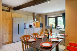 een keuken met een tafel en stoelen en een koelkast bij Le Clos Arboré (Gîte) in Libramont