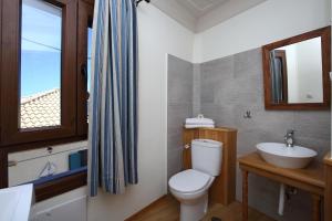 baño con aseo y lavabo y ventana en Stafilos House, en Katouna