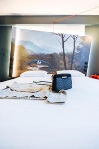 a bed with a picture and a cell phone on it at ibis Styles Le Mans Gare Sud in Le Mans
