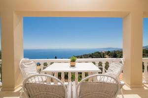 a balcony with a table and chairs and the ocean at Armyra Villas in Volimes