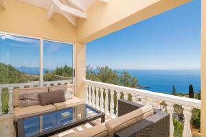 balcón con sofá y vistas al océano en Armyra Villas, en Volímai