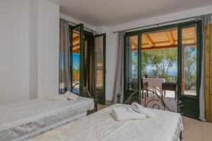 a bedroom with two beds and a balcony at Armyra Villas in Volimes
