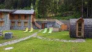 um quintal com cadeiras verdes e uma casa em Chalet Resort Sozzine em Ponte di Legno