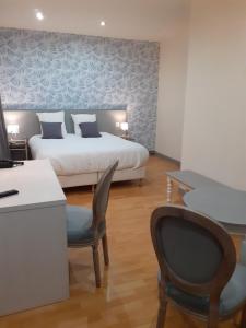 Schlafzimmer mit einem Bett, einem Schreibtisch und Stühlen in der Unterkunft Logis Hôtel Restaurant de l'Ecu in Montbard