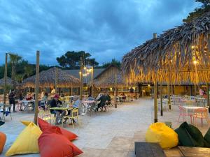 een restaurant met tafels en stoelen en rieten parasols bij Volare Camp in Villaggio San Francesco in Duna Verde