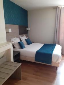 a bedroom with a bed with blue and white pillows at Logis Hôtel Restaurant de l'Ecu in Montbard +4 photos