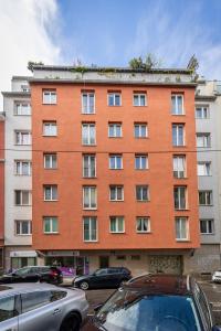 duży pomarańczowy budynek z samochodami zaparkowanymi przed nim w obiekcie BRIGHT + CENTRAL near Belvedere by JR City Apartments w Wiedniu