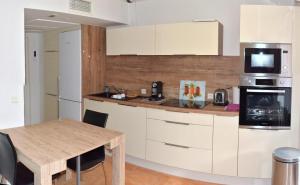 a kitchen with white cabinets and a wooden table at L'Orangeraie du Cap in Antibes