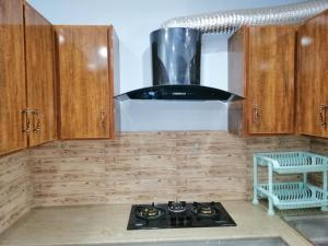 uma cozinha com armários de madeira e um forno com placa de fogão em Full Private House Floor with Lounge & Balcony - Townhouse - Homestay em Lahore