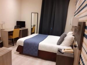 Schlafzimmer mit einem Bett und einem Schreibtisch mit einem Computer in der Unterkunft Logis Hôtel Restaurant de l'Ecu in Montbard