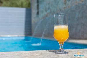 a glass of orange juice sitting on a table next to a pool at Villa Arion in Nydri +8 photos