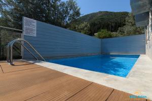 a swimming pool with a wooden deck and a blue wall at Villa Arion in Nydri