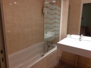 ein Bad mit einer Badewanne, einem Waschbecken und einer Dusche in der Unterkunft Logis Hôtel Restaurant de l'Ecu in Montbard
