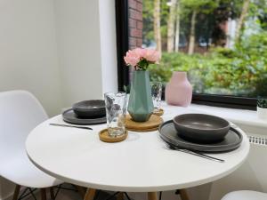 a white table with plates and a vase with flowers at Southernhay Court Apartments by Staytor Accommodation in Exeter