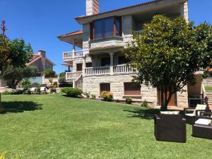 a large stone house with a lawn and trees at APARTAMENTOS MAR DE AREAS in Sanxenxo