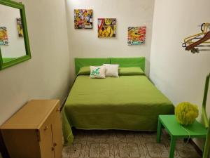 ein kleines Schlafzimmer mit einem grünen Bett und einem Spiegel in der Unterkunft Casa Pinù in Pachino