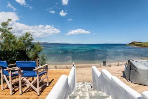 um par de cadeiras sentadas num deque com vista para a praia em Bay View Suites em Agios Nikolaos