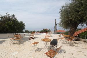 a patio with tables and chairs and a tree at White Hotel in Borsh