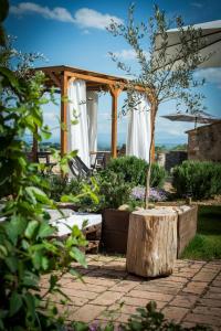 einen Garten mit einer hölzernen Pergola und einem Baumstumpf in der Unterkunft Palazzo del Papa Country Suites in Siena