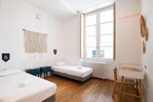 a room with two beds and a window at SLO Hostel Lyon les Pentes in Lyon