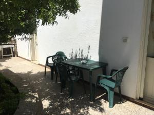 een groene tafel en stoelen naast een gebouw bij La casa di Donato in Gagliano del Capo
