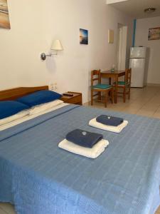 Un dormitorio con una cama azul con toallas. en Angelos Studios, en Ilia