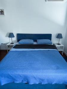 a blue bed with a blue comforter and two lamps at Apartment Azzurro lux in Novi Beograd