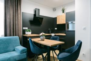 Jarila Boutique Apartment في براتيسلافا: مطبخ مع طاولة خشبية وكراسي زرقاء
