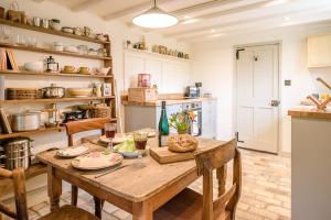 a kitchen with a wooden table and chairs and a kitchen with shelves at The Wash House Middleton Air Manage Suffolk in Saxmundham