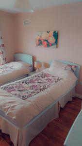a bedroom with two beds and a painting on the wall at Lios na Mara Lahinch in Lahinch