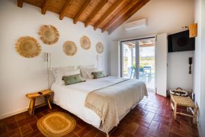 a bedroom with a large bed and a balcony at Monte da Bemposta in Porto Covo