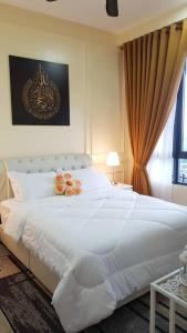 a bedroom with a large white bed with fruit on it at Aleeya Suite @ Troika Residence in Kota Bharu