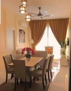 a dining room with a table and chairs and a couch at Aleeya Suite @ Troika Residence in Kota Bharu