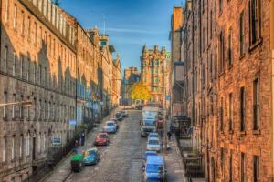 a city street with cars parked on the street between buildings at Turtle Apartment in Edinburgh