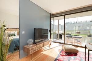 uma sala de estar com uma televisão de ecrã plano na parede em Feel Corporate Housing Campanhã no Porto