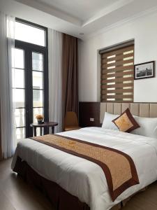 una camera con un grande letto e una grande finestra di VĨNH KHANG HẠ LONG HOTEL a Ha Long