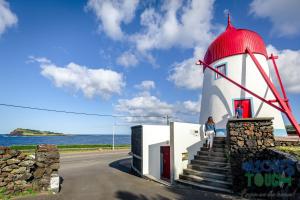 a woman walking up the stairs to a lighthouse at Boina de Vento in Santa Cruz da Graciosa