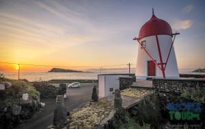 un faro con la puesta de sol en el fondo en Boina de Vento, en Santa Cruz da Graciosa