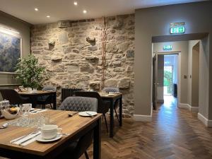a restaurant with tables and chairs and a stone wall at Ben Cruachan Guest House in Edinburgh