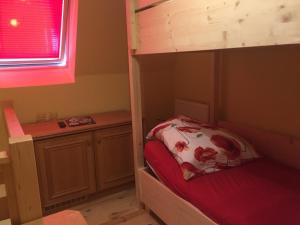 a bedroom with a bunk bed with a red bedsheet at Kérész Panzió in Mártély