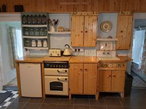 a kitchen with wooden cabinets and a stove top oven at CherryTreeCottage - Cosy 19thCentury Pet Friendly in Claragh