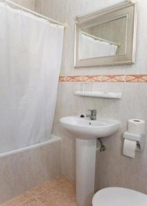 a bathroom with a sink and a toilet and a mirror at Hotel Playa Sol in El Arenal