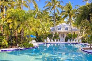 a swimming pool in front of a house with palm trees at Charming Boho Breeze Retreat with Pool Access in Key West